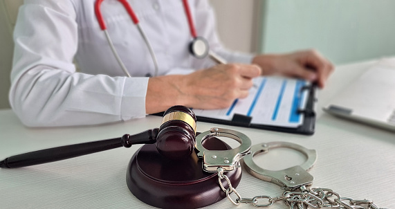 Judge gavel of stethoscope doctor in background writing notes. Concept of legal aspects of healthcare and medical insurance payments